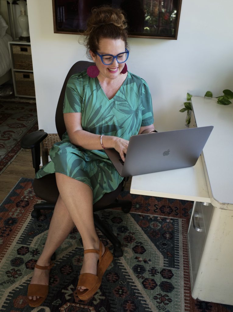 Woman in green dress at desk and computer.